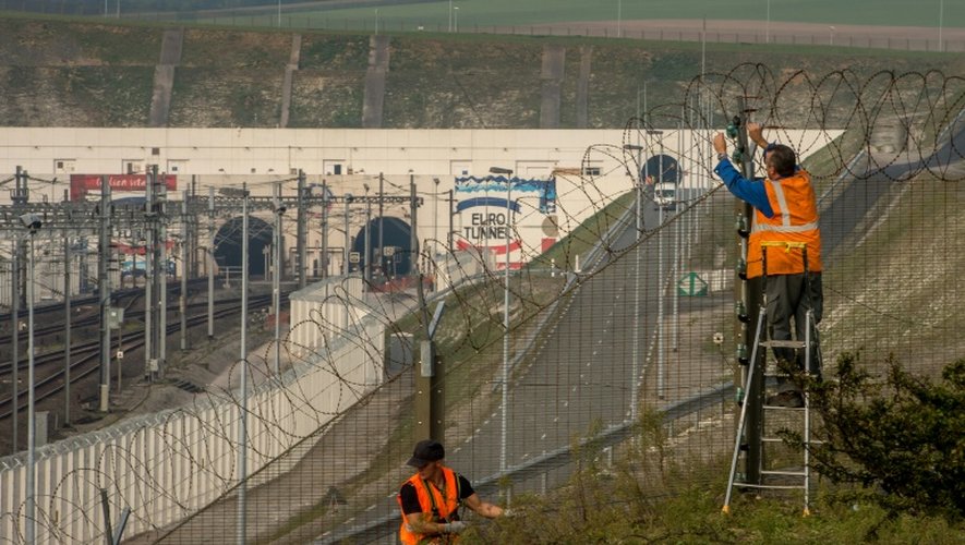 Des ouvriers réparent la clôture sécurisant l'Eurotunnel à Coquelles près de Calais le 3 octobre 2015