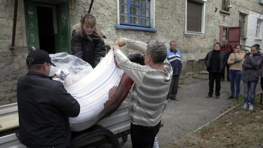 Des habitants de Debaltseve transportent le corps d'une femme tuée dans le bombardement de son immeuble, le 22 septembre 2014 dans la région de Donetsk