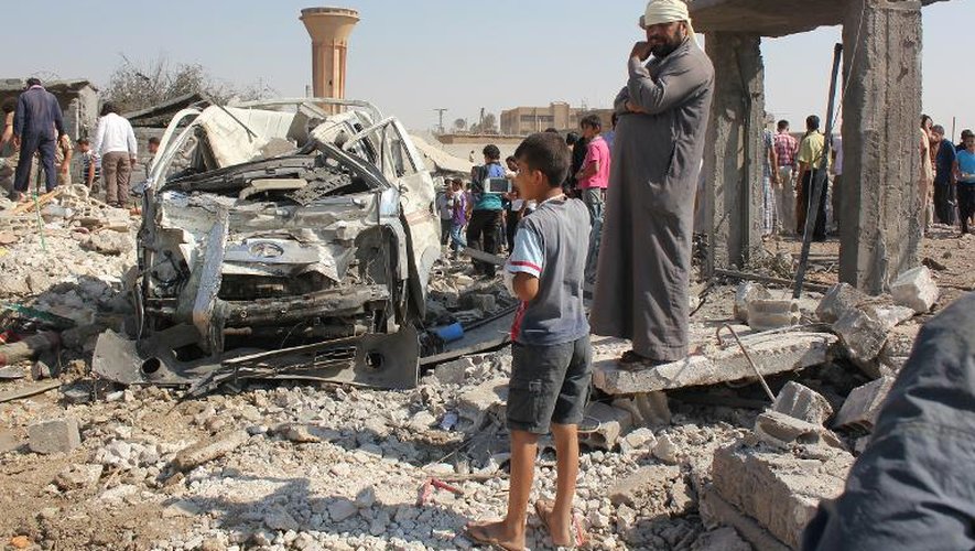 Des civils le 16 septembre 2014 près d'un véhicule des forces syriennes abattu par les jihadistes à Raqa