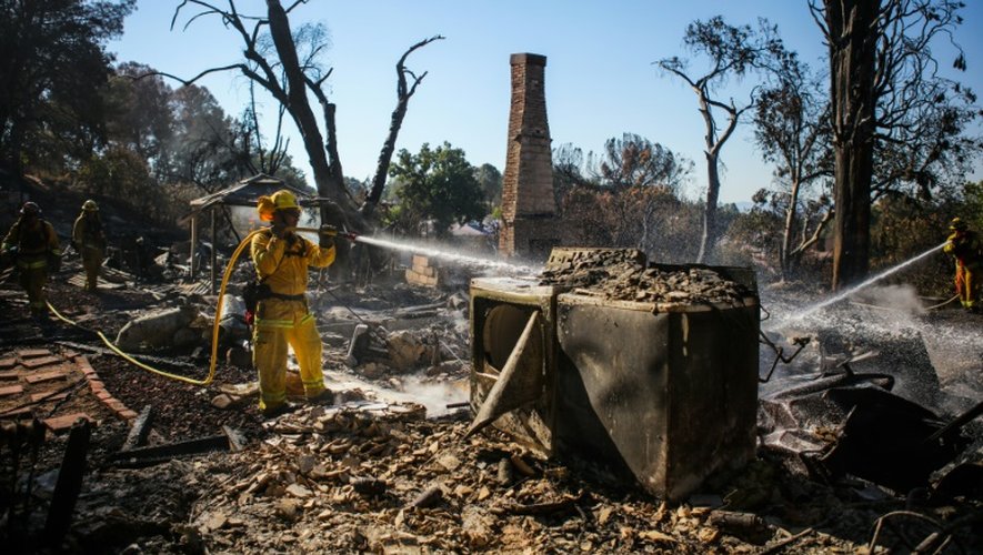 Des pompiers luttent contre les reprise de feu dans les ruines d'une maison à Lower Lake, le 15 août 2016 en Californie