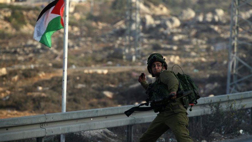 Un soldat israélien lance une grenade lacrymogène en direction de jeunes Palestiniens, lors de heurts à Ramallah, le 4 octobre 2015