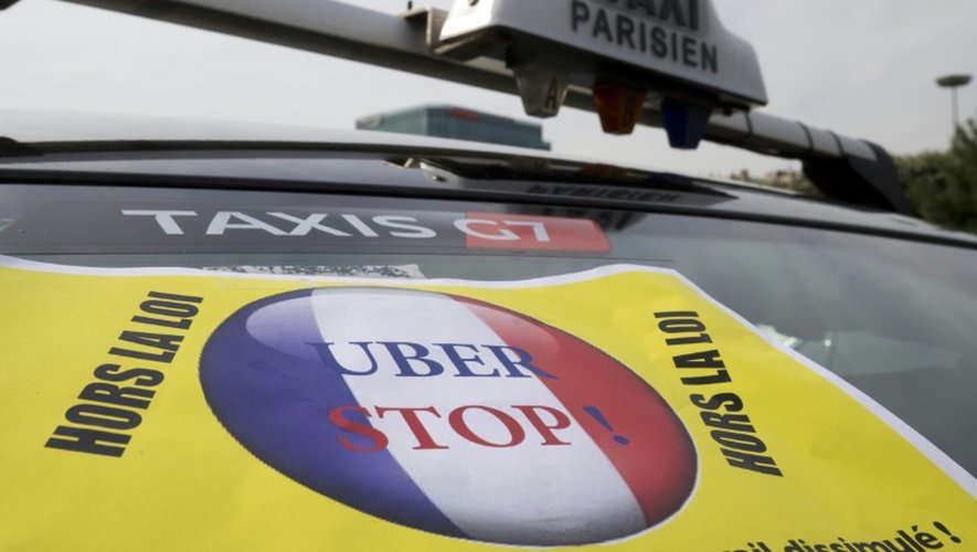 Une affiche anti-Uber sur un taxi qui bloque la porte Maillot, à Paris, le 26 juin 2015 lors d'un mouvement de grève contre le géant des véhicules de transport avec chauffeurs, Uber