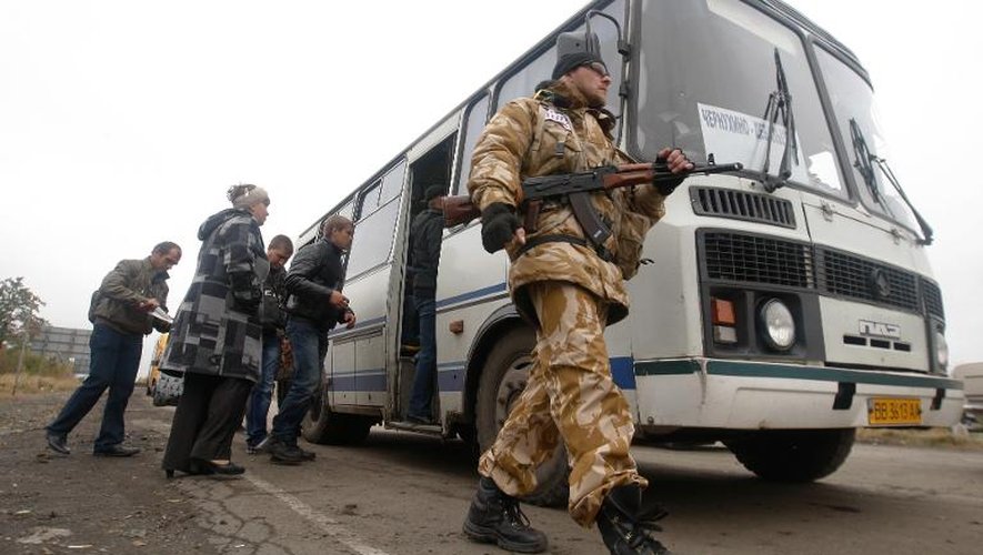 Un soldat ukrainien contrôle les papiers d'identité des passagers d'un bus à un check-pointprès de Debaltseve, dans la région de Donetsk, le 25 septembre 2014