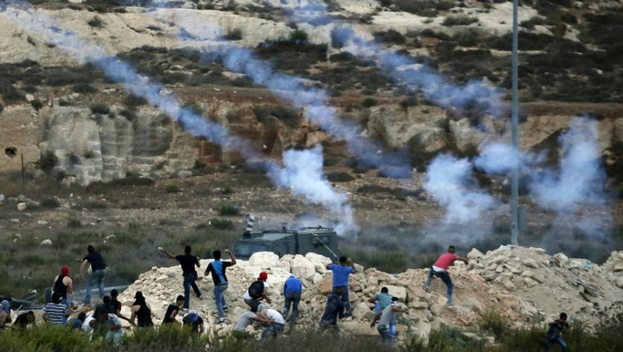 Des forces de sécurité israéliennes tirent des grenades lacrymogènes sur des jeunes Palestiniens qui leur lancent des pierres, le 5 octobre 2015 au nord de Ramallah