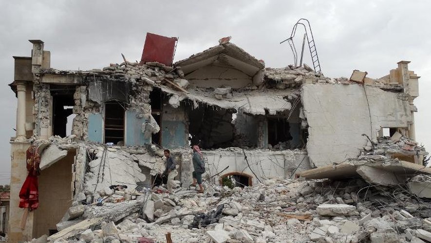 Des habitants au milieu des ruines d'u bâtiment après un nouveau raid aérien américain contre le siège du Front Al-Nosra, à 20 km à l'ouest de la ville d'Alep, le 25 septembre 2014 en Syrie