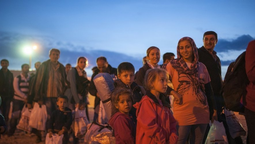 Des migrants et réfugiés attendent à l'entrée d'un camp d'enregistrement après avoir franchi la frontière entre la Grèce et la Macédoine, le 6 octobre 2015 près de Gevgelija