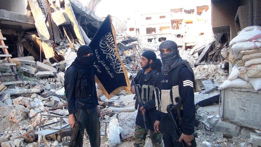 Des combattants du Front Al-Nosra, branche syrienne d'Al-Qaïda, devant des immeubles bombardés, dans le camp de réfugiés palestiens à Yarmouk, dans le sud de Damas, le 22 septembre 2014