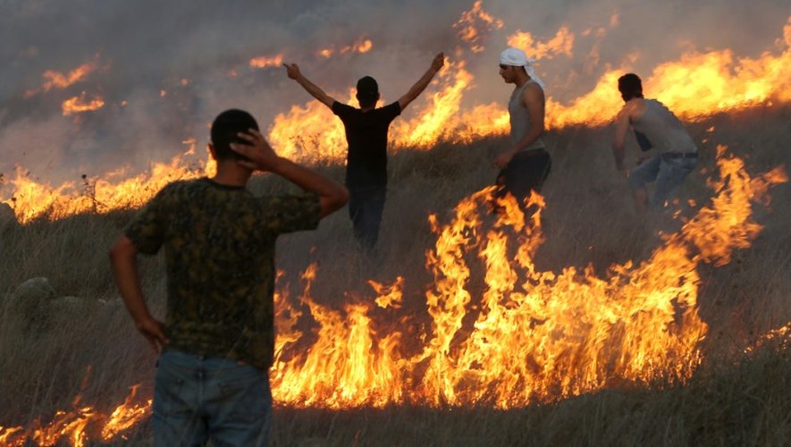 Des manifestants palestiniens au milieu des flammes, lors d'affrontements avec des colons israéliens, dans le village de Burin, en Cisjordanie, le 3 octobre 2015