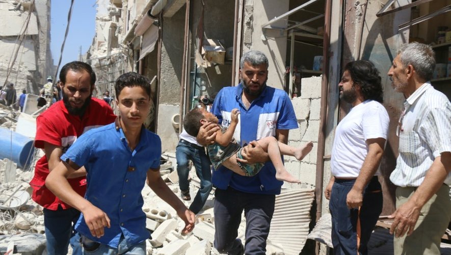 Un volontaire de la Défense civile syrienne porte un enfant blessé par les bombardements à Alep le 23 juillet 2016
