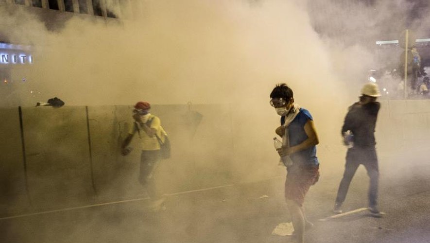 Des manifestants se protègent des gaz lacrymogènes à Hong Kong le 28 septembre 2014
