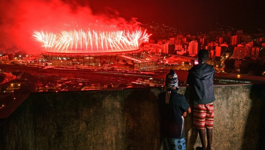 Des enfants de la favela Mangueira regardent les feux d'artifices tirés au-dessus du Maracana pour la cérémonie de clôture des Jeux le 21 août 2016 à Rio
