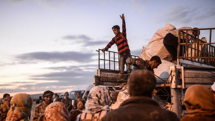 Des Kurdes syriens chargent leurs bagages sur un camion vers Suruc après avoir traversé la frontière entre la Syrie et la Turquie le 30 septembre 2014