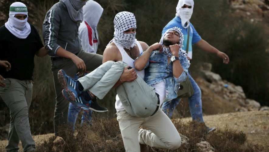 Un jeune palestinien est évacué par ses camarades après avoir été touché lors d'affrontements avec la police israélienne à Beit El (Cisjordanie), le 10 octobre 2015