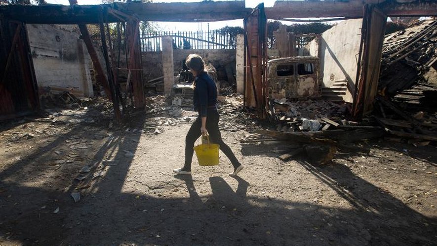 Une femme transporte de l'eau, dans la cour d'un hôpital détruit par des tirs de roquette, dans la ville de Popasna, le 1er octobre 2014