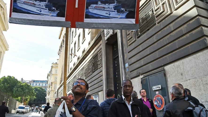 Un employé de la SNCM brandit des affiches des navires de la compagnie, le 25 septembre 2015 devant le palais de justice de Marseille