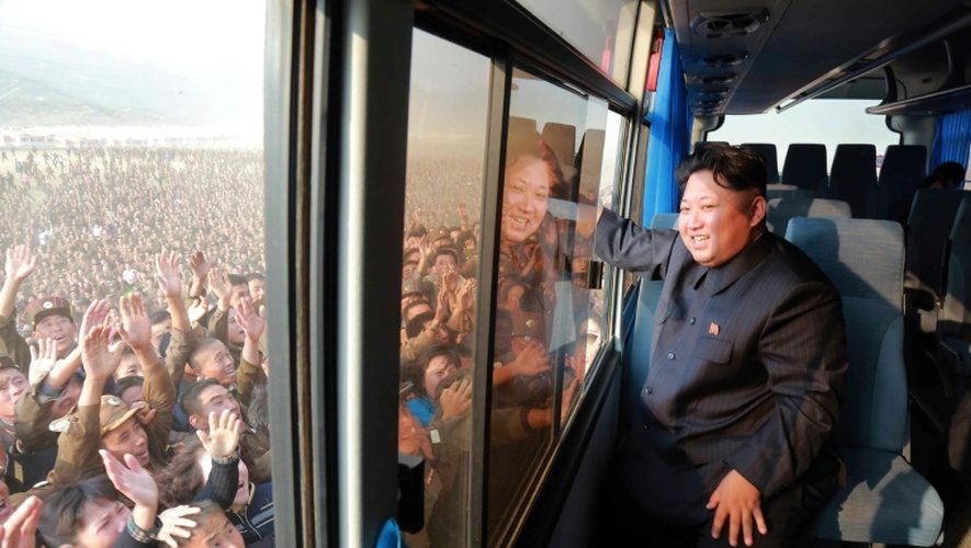 Photo diffusée par l'agence officielle nord-coréenne Korean Central News Agency (KCNA) le 8 octobre 2015 montrant le dirigeant Kim Jong-Un saluant la foule depuis un autobus pendant qu'il inspecte un nouveau village Paekhak-dong dans le district de Sonbong