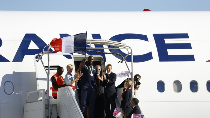 Le double médaillé d'or olympique en judo Teddy Riner, drapeau à la main, à sa descente de l'avion de retour des Jeux de Rio sur le tarmac de l'aéroport Charles de Gaulle à Roissy le 23 août 2016