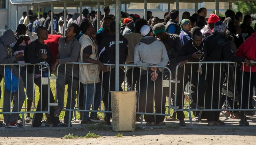 Des migrants font la queue pour recevoir de la nourriture distribuée par l'association "Vie Active" au centre d'aide humanitaire Jules-Ferry  proche de la "Jungle" le 22 août 2016 à Calais