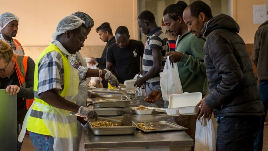 Des migrants reçoivent la nourriture distribuée par l'association "Vie Active" au centre d'aide humanitaire Jules-Ferry  proche de la "Jungle" le 22 août 2016 à Calais