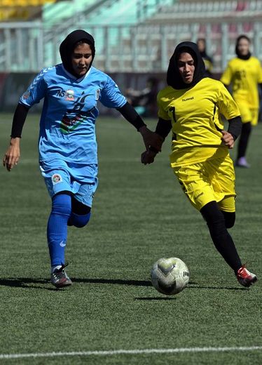La joueuse de l'équipe féminine de foot de Kaboul Madina Azizi (d) et sa rivale d'Hérat s'affrontent en finale du premier championnat de foot féminin d'Afghanistan, à Kaboul, le 3 octobre 2014