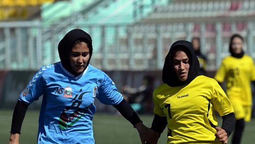 La joueuse de l'équipe féminine de foot de Kaboul Madina Azizi (d) et sa rivale d'Hérat s'affrontent en finale du premier championnat de foot féminin d'Afghanistan, à Kaboul, le 3 octobre 2014