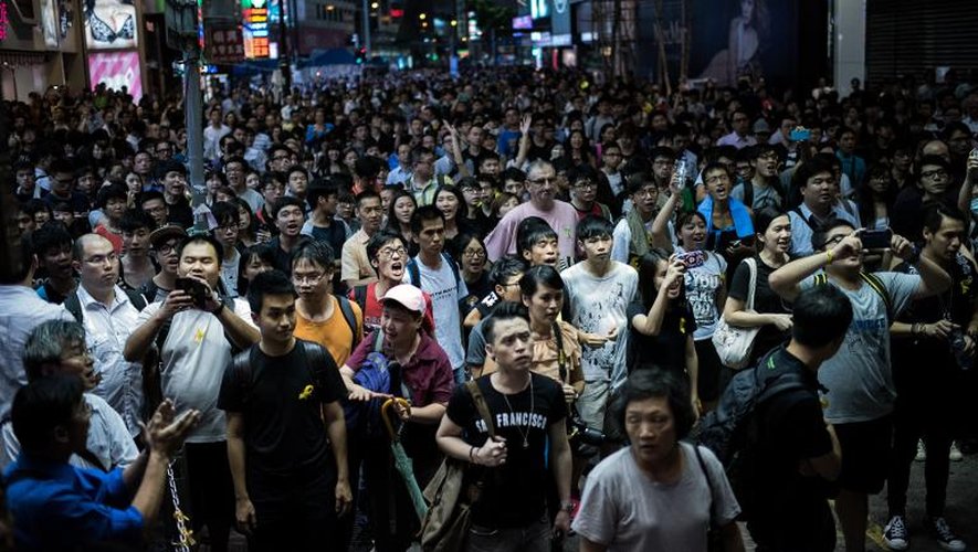 Des gens dans la rue observent la police embarquer des barricades qui avait été déployées devant  des manifestants prodémocratie à Causeway Bay à Hong Kong le 3 octobre 2014