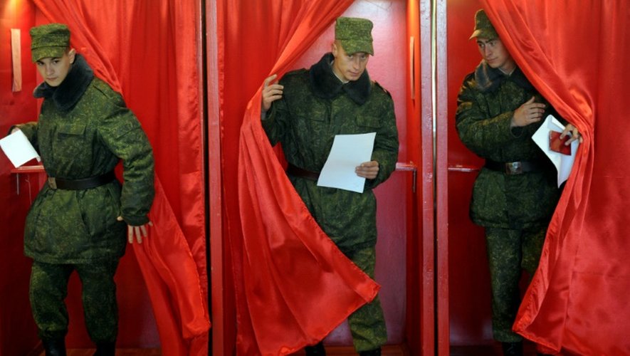 Des soldats bélarusses quittent l'isoloir après avoir voté à l'élection présidentielle dans le bureau de vote de Bogushi à Minsk le 11 octobre 2015