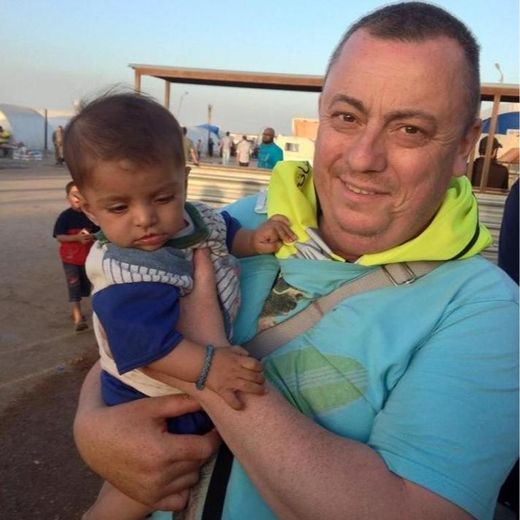 Le travailleur humanitaire britannique Alan Hennning, portant un enfant dans un camp de réfugiés à la frontière entre la Syrie et la Turquie, dans une photo fournie le 15 septembre 2014 par le Foreign Office
