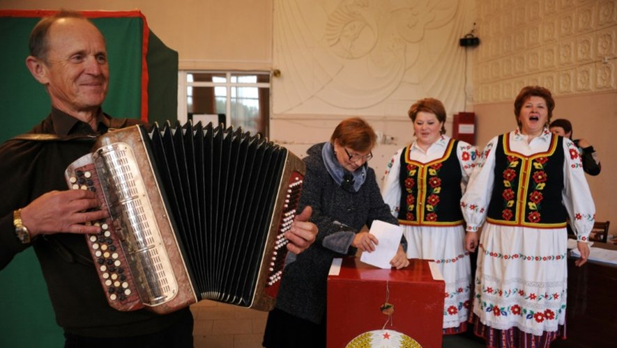 Un homme joue de l'accordéon et des femmes chantent des airs folkloriques pendant que les gens votent dans un bureau de vote dans le village de Sinki à 130 kilomètres au nord-ouest de Minsk le 11 octobre 2015