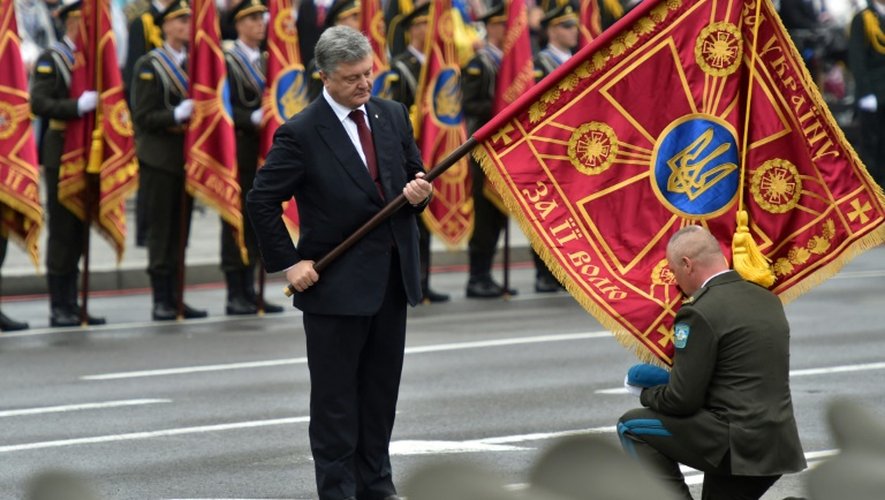 Le commandant d'une unité rend hommage au drapeau que lui tend le président ukrainien Petro Porochenko, à Kiev, le 24 août 2016
