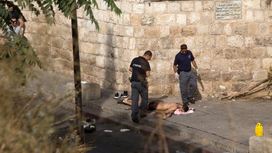 Des médecins légistes israéliens examinent le corps d'un Palestinien qui a agressé au couteau un policier avant d'être abattu par d'autres policiers, le 12 octobre 2015 à Jérusalem