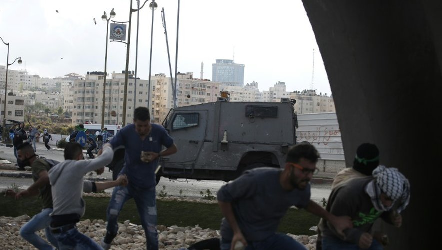 Des Palestiniens lanceurs de pierre se mettent à couvert alors que les forces de sécurité israéliennes tirent des balles en caoutchouc depuis un véhicule, le 8 octobre 2015 à Ramallah