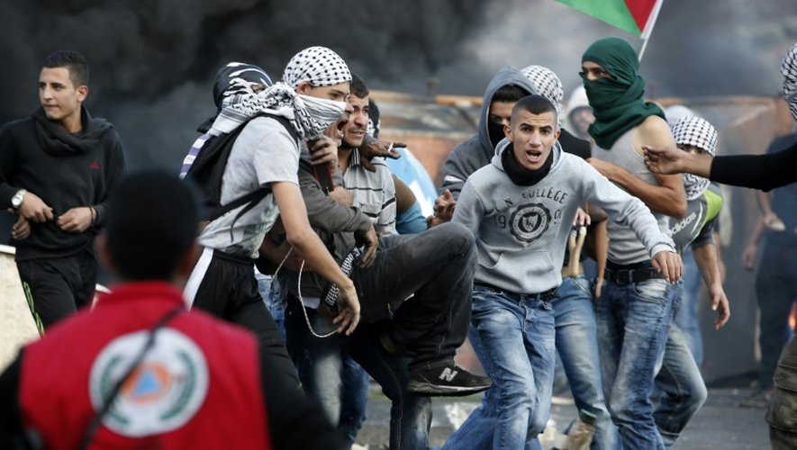 Des Palestiniens emmènent un camarade blessé à la jambe lors de heurts avec les forces de sécurité israéliennes, le 9 octobre 2015 à Ramallah