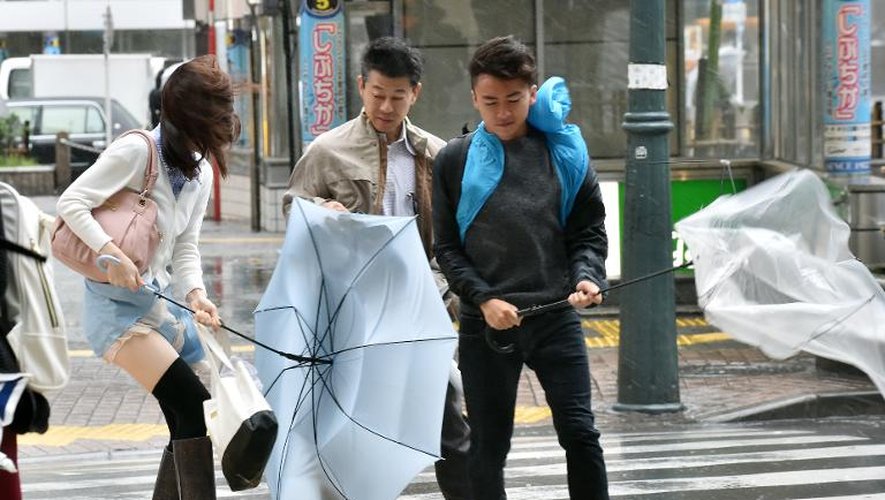 Des piétons luttent contre le vent et la pluie lors du passage du typhon Phanfone au Japon, le 6 octobre 2014 à Tokyo