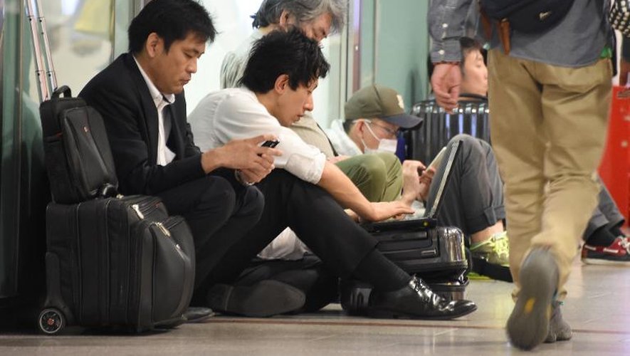 Des voyageurs attendent à la gare après une interruption du trafic des trains due au passage du typhon Phanfone, le 6 octobre 2014 à Tokyo