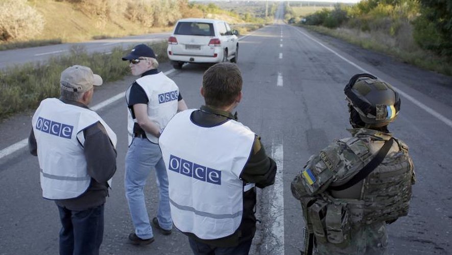 Des observateurs de l'OSCE et un soldat ukrainien sur une route près de Donetsk, le 20 septembre 2014 avant un échange de prisonniers