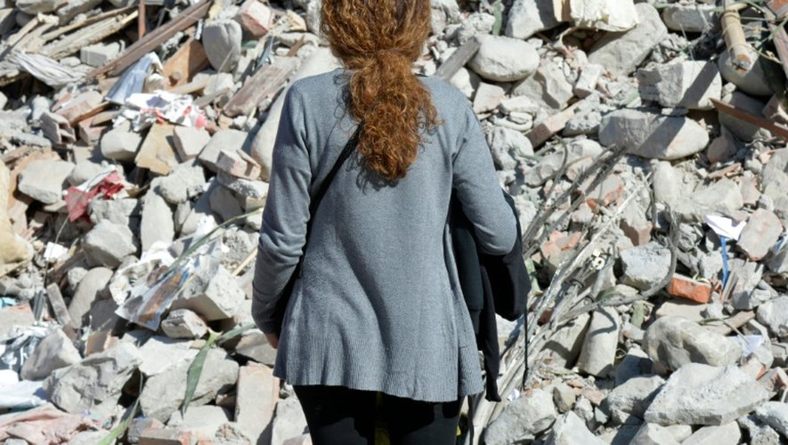 Une femme devant les décombres d'un immeuble détruit par le séisme à Amatrice, le 26 août 2016