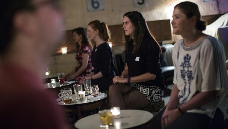 Des hommes et des femmes face à face lors d'un "shhh dating" ou rencontre silencieuse, dans un bar à l'est de Londres le 23 septembre 2015