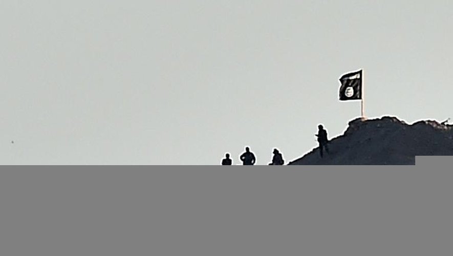 Des jihadistes du groupe Etat islamique plantent un drapeau noir de l'EI sur une colline de la ville de Kobané, le 6 octobre 2014 en Syrie