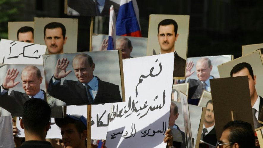Plusieurs centaines de personnes brandissant des portraits des présidents russe et syrien sont réunies le 13 octobre 2015 près de l'ambassade russe à Damas pour exprimer leur soutien à l'intervention russe
