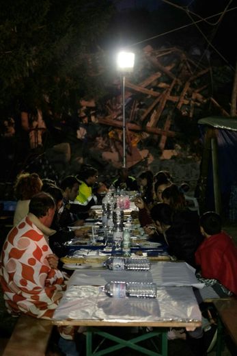 Des habitants d'Illica prennent le dîner dans un village de tente improvisé, le 25 août 2016, au lendemain du violent séisme qui a dévasté ce hameau d'Accumoli, dans les montagnes du Latium