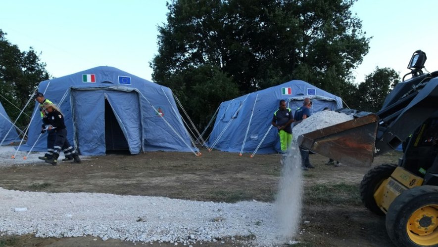 Des volontaires déversent du gravier dans un village de tente installé pour les victimes du séisme à Accumoli, dans le centre de l'Italie, le 25 août 2016