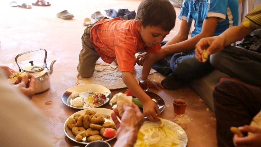 Une famille syrienne évacuée de la ville de Daraya, reprise par le régime, partage un petit déjeuner à son arrivée à Hrajela le 27 août 2016