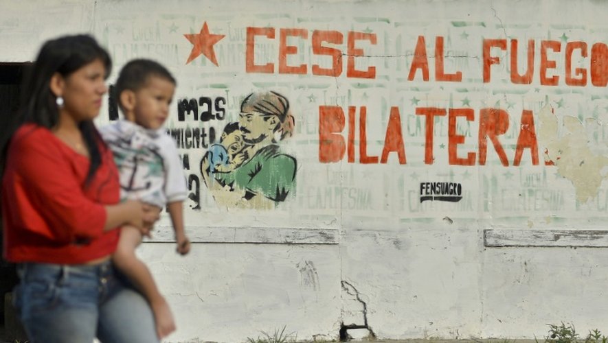 Une femme et son enfant devant une fresque qui dit "Cessez-le-feu bilatéral", le 28 août 2016 dans une rue d'El Palo, département de Cauca, en Colombie