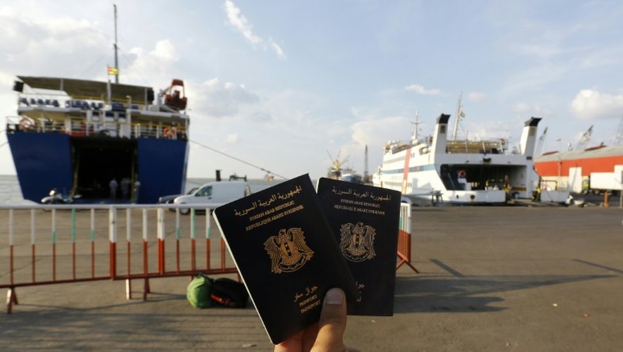 Un Syrien montre ses passeports syriens en attendant le ferry à Tripoli au Liban qui va le conduire en Turquie, le 6 octobre 2015