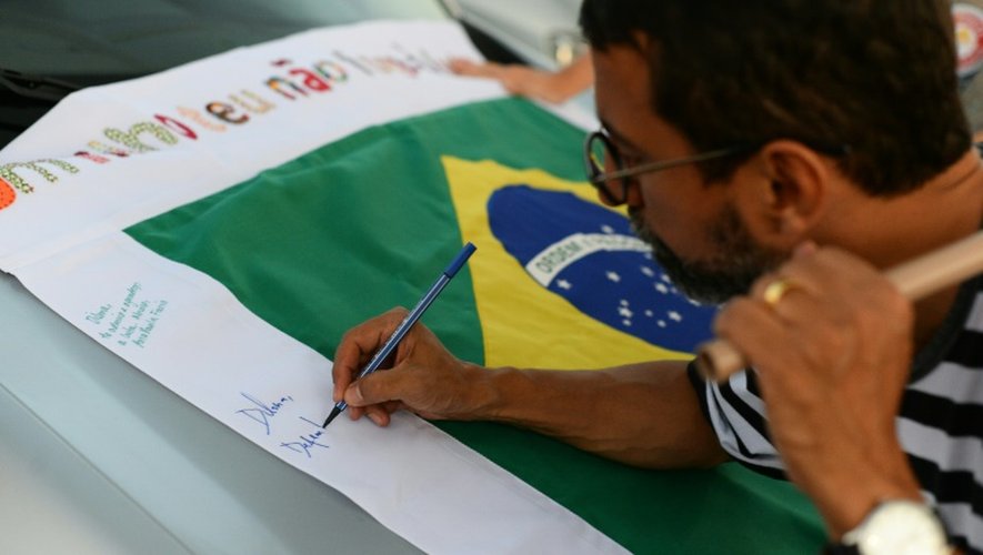 Un manifestant soutien de Dilma Rousseff, le 28 août, signe un drapeau brésilien qui sera remis à la présidente suspendue lors de son apparition à son procès en destitution le lendemain, à Brasilia