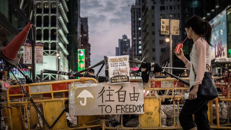 Une femme passe devant une barricade érigée par les militants prodémocratie, le 9 octobre 2014 à Hong Kong
