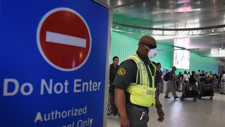 Un employé de l'aéroport de Los Angeles, le 9 octobre 2014, porte un masque de protection dans la zone des arrivées après l'annonce par les Etats-Unis d'un renforcement du contrôle des voyageurs en provenance des pays africains touchés par le virus Ebola