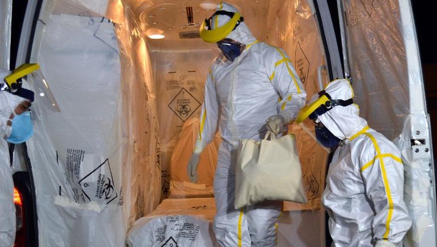 Des agents médicaux en combinaison de protection préparent une ambulance pour transporter un Guinéen suspecté d'avoir contracté le virus Ebola, le 10 octobre 2014 à Cascavel, dans l'Etat du Parana, au Brésil
