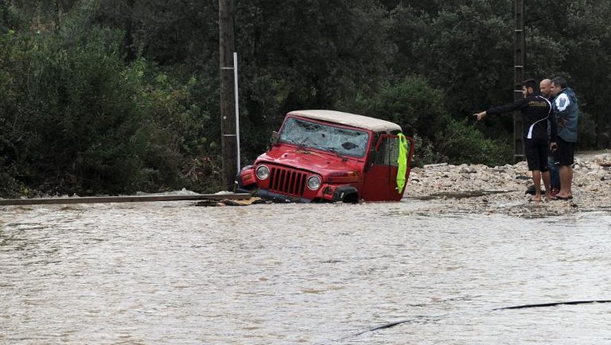 Des habitants de Nîmes à côté d'un véhicule inondé, le 10 octobre 2014 dans le Gard